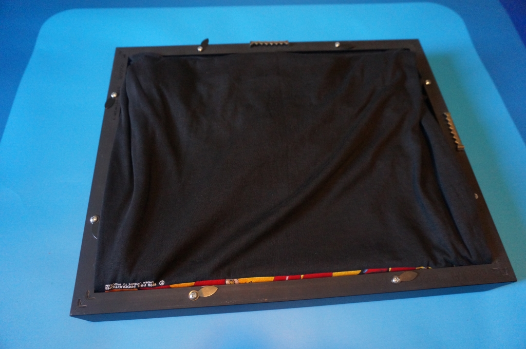 neatly organize the remaining fabric of the shirt inside the frame